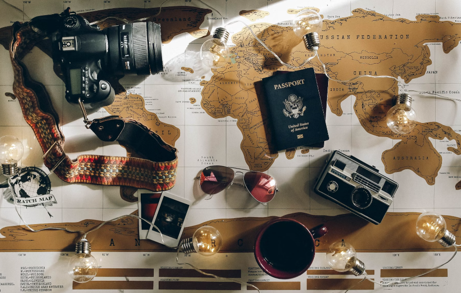 camera passport sunglasses photos coffee on top of a world map